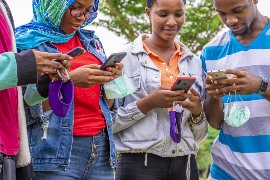 a picture of four young people with their phones to depict workers in a social media agency who are working on social shares